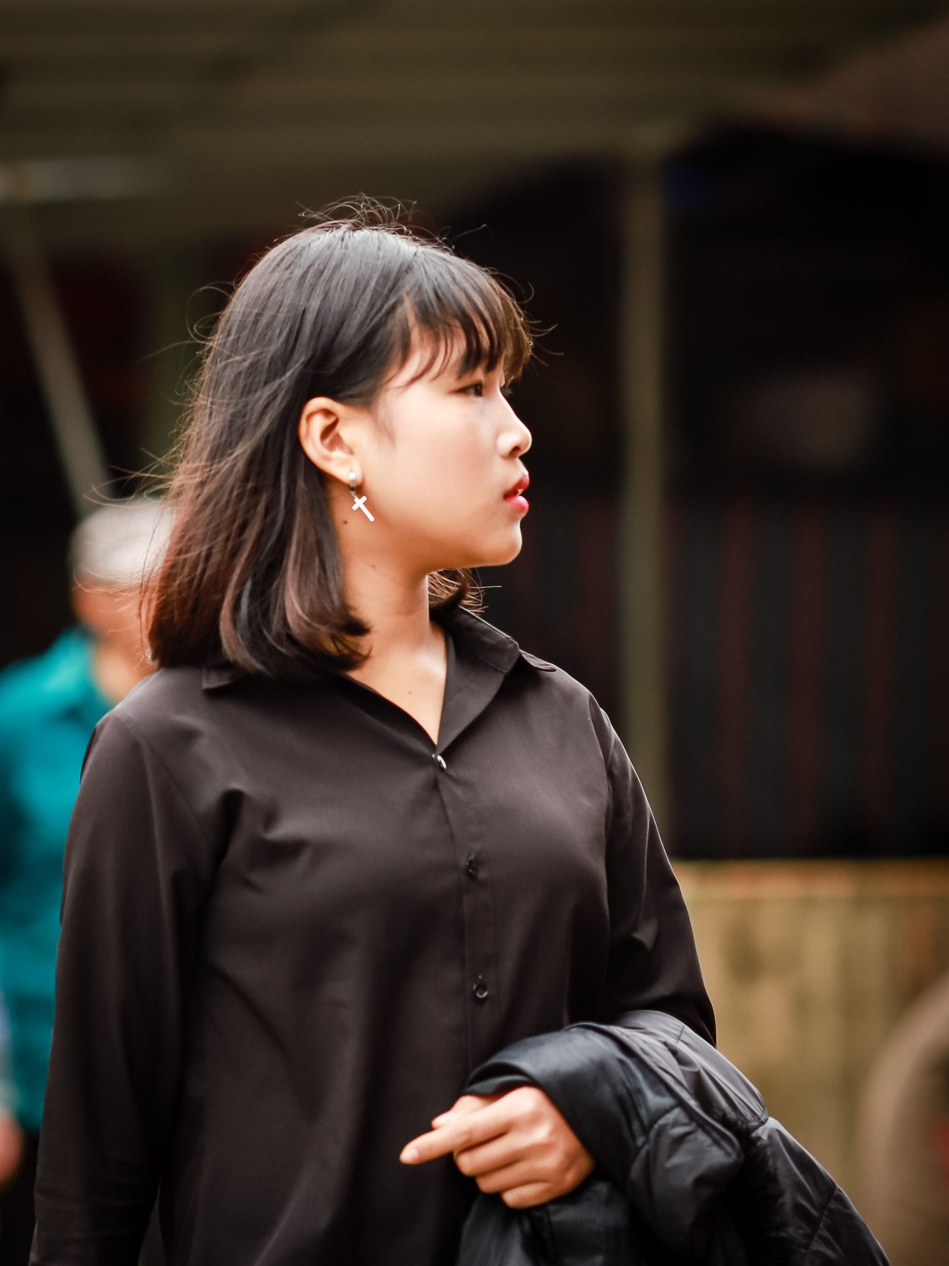 A young woman with earrings stands outdoors in Lào Cai, Việt Nam.