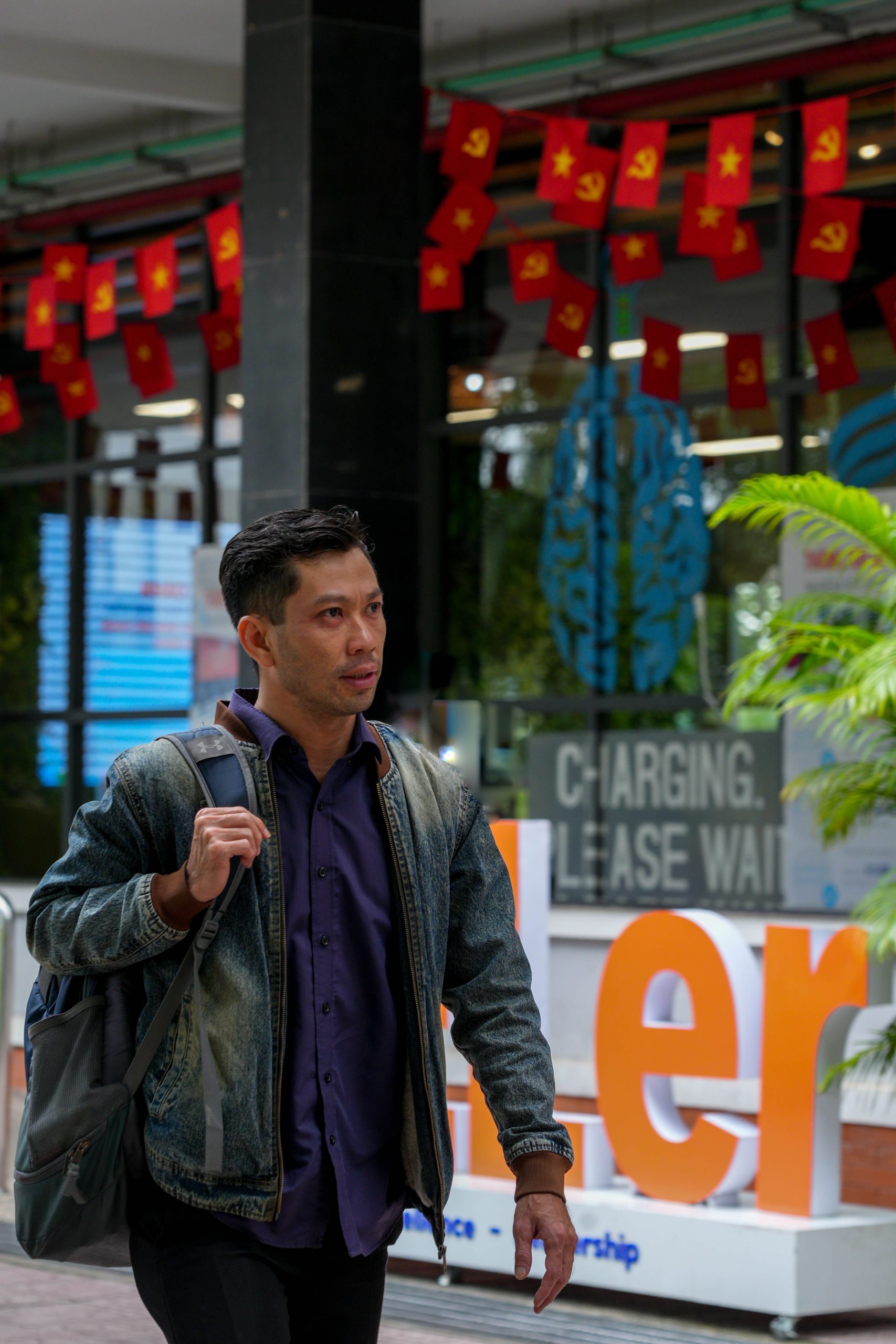 A man walks by a storefront adorned with flags and vibrant display.